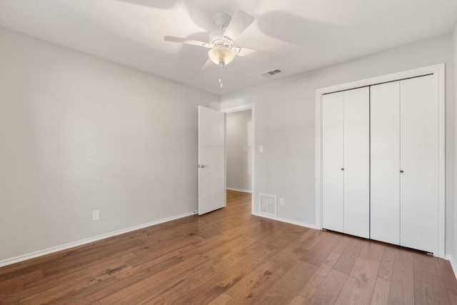 unfurnished bedroom featuring baseboards, visible vents, and wood finished floors