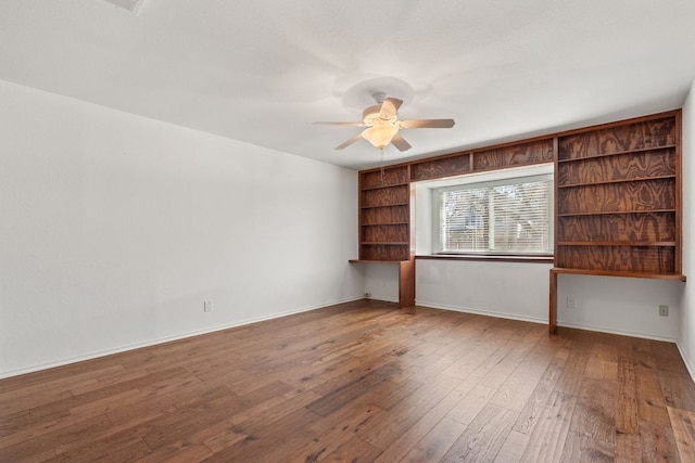 spare room with wood-type flooring, a ceiling fan, and baseboards