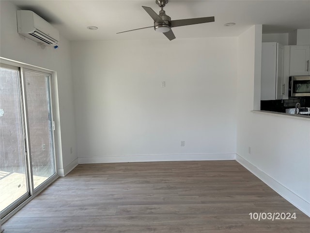 interior space featuring ceiling fan, an AC wall unit, and light wood-type flooring