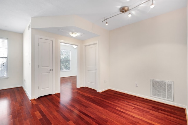 spare room featuring rail lighting and dark hardwood / wood-style flooring