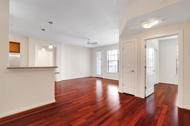 unfurnished living room featuring dark wood-type flooring and ceiling fan