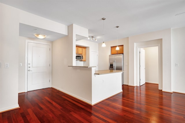 kitchen featuring hanging light fixtures, kitchen peninsula, stainless steel appliances, a breakfast bar, and dark hardwood / wood-style flooring