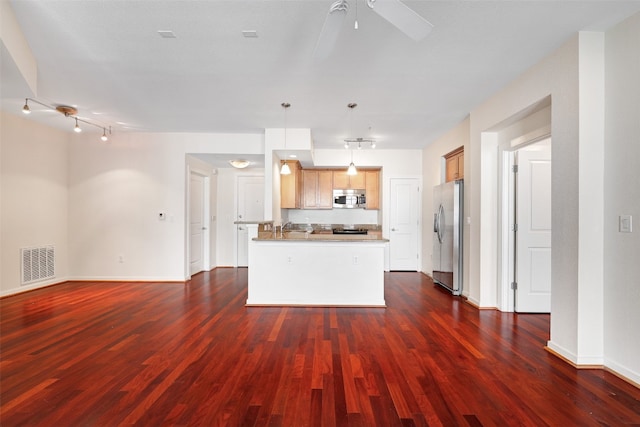 kitchen with a center island with sink, appliances with stainless steel finishes, decorative light fixtures, and dark hardwood / wood-style floors