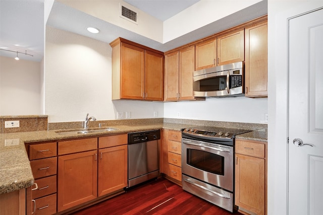 kitchen featuring track lighting, light stone countertops, dark hardwood / wood-style floors, sink, and stainless steel appliances