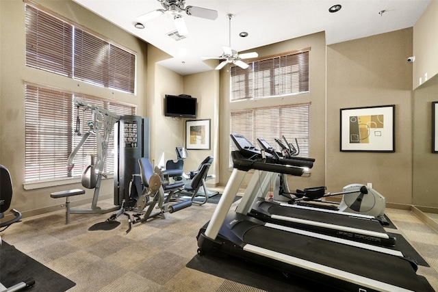 workout area featuring ceiling fan, light carpet, and a towering ceiling