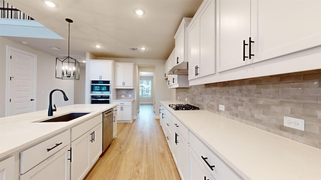 kitchen with appliances with stainless steel finishes, white cabinetry, hanging light fixtures, and sink