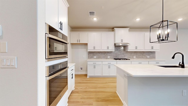 kitchen featuring pendant lighting, an inviting chandelier, white cabinetry, and sink