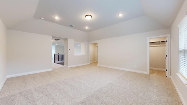 empty room featuring light colored carpet, vaulted ceiling, and a healthy amount of sunlight