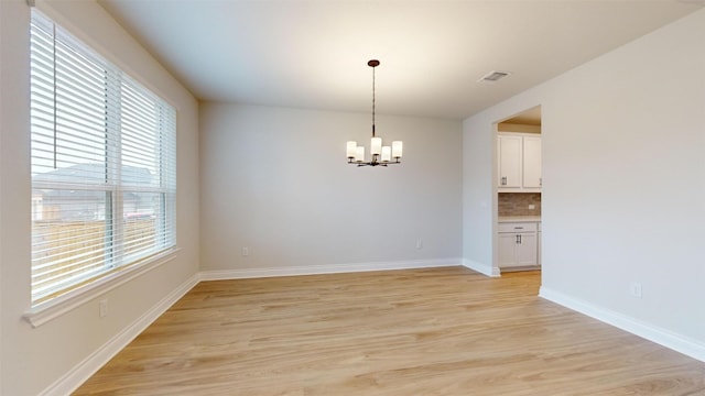 empty room with a notable chandelier and light wood-type flooring