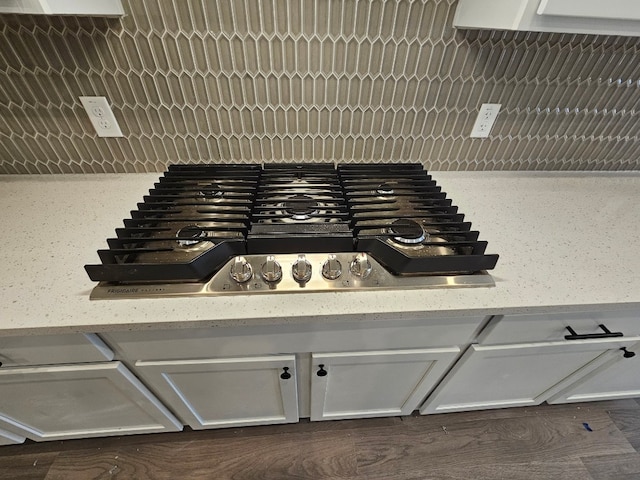 interior details with white cabinetry, light stone countertops, and gas stovetop