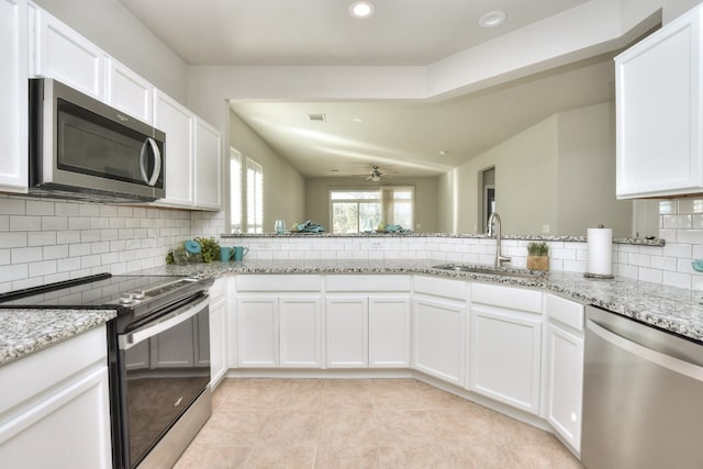 kitchen featuring tasteful backsplash, light stone countertops, sink, stainless steel appliances, and white cabinets