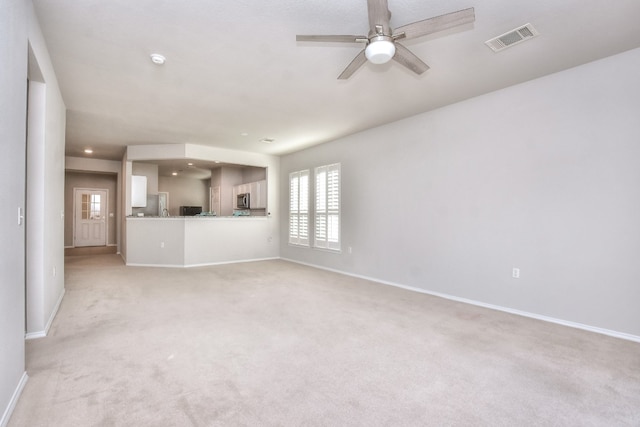 unfurnished living room featuring light carpet and ceiling fan