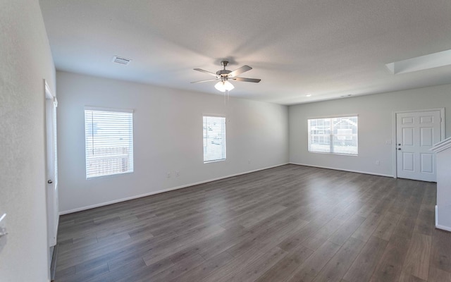 unfurnished room with ceiling fan, a textured ceiling, a skylight, and dark hardwood / wood-style floors