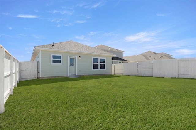 196 Lavender Ln, Elgin, TX 78621 - back of property with a fenced backyard, a shingled roof, and a lawn