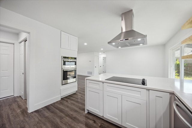 kitchen featuring appliances with stainless steel finishes, wall chimney exhaust hood, white cabinets, and dark wood-type flooring