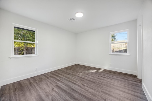 empty room featuring a healthy amount of sunlight and dark hardwood / wood-style flooring