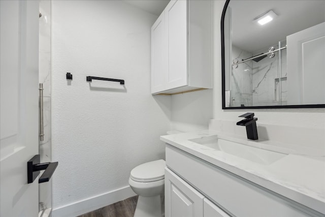 bathroom with vanity, hardwood / wood-style floors, tiled shower, and toilet