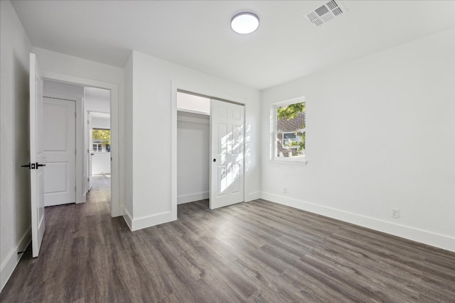 unfurnished bedroom with a closet and dark wood-type flooring