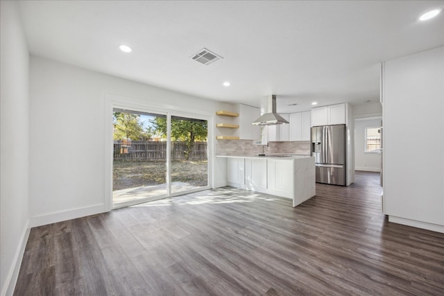 kitchen with stainless steel fridge, white cabinets, kitchen peninsula, and plenty of natural light