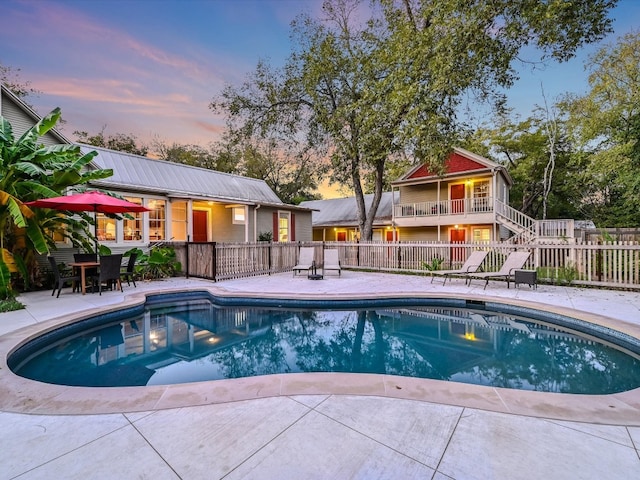 pool at dusk featuring a patio area