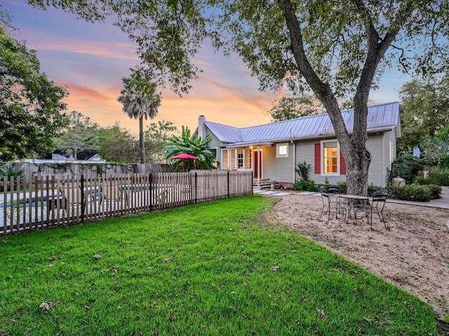 exterior space with a lawn, a standing seam roof, fence private yard, and metal roof