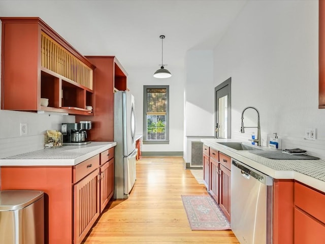 kitchen with open shelves, light countertops, a sink, light wood finished floors, and appliances with stainless steel finishes