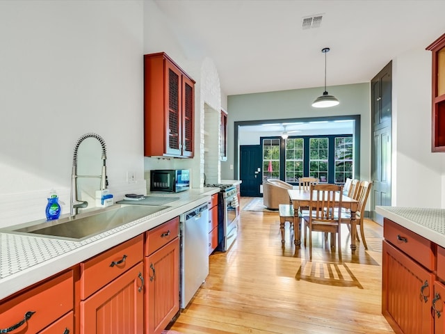 kitchen featuring sink, light wood-type flooring, hanging light fixtures, ceiling fan, and stainless steel appliances