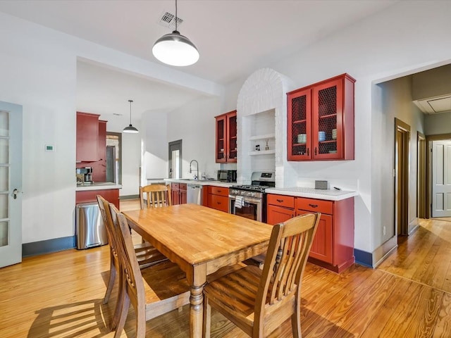 dining room featuring visible vents, light wood-style floors, baseboards, and beam ceiling