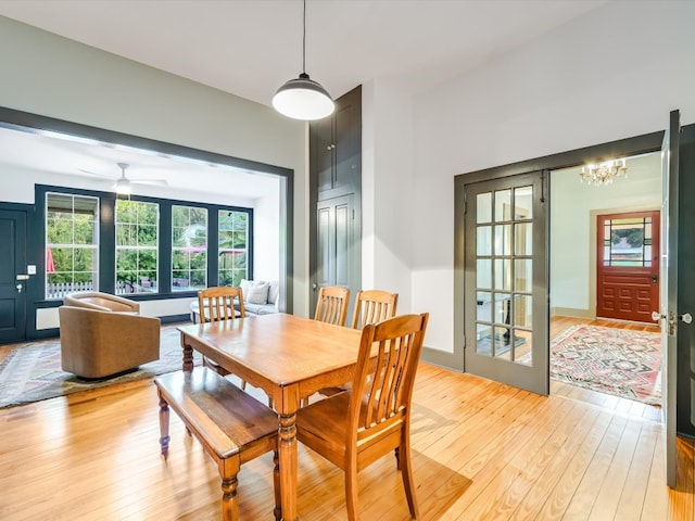 dining space featuring light hardwood / wood-style floors and ceiling fan with notable chandelier