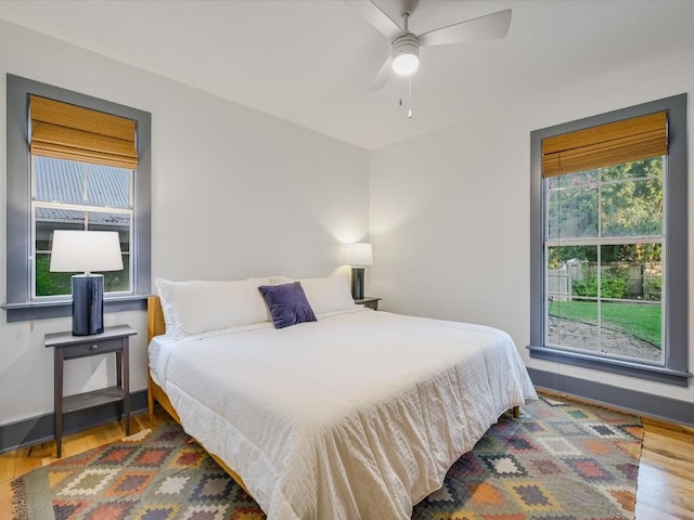bedroom with a ceiling fan, baseboards, and wood finished floors