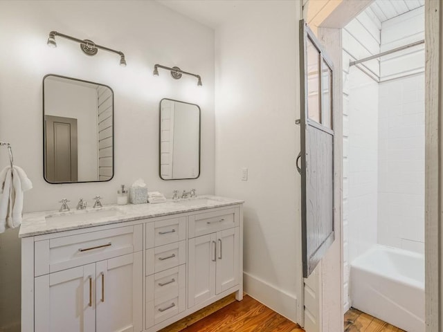 full bathroom with double vanity, a sink, and wood finished floors