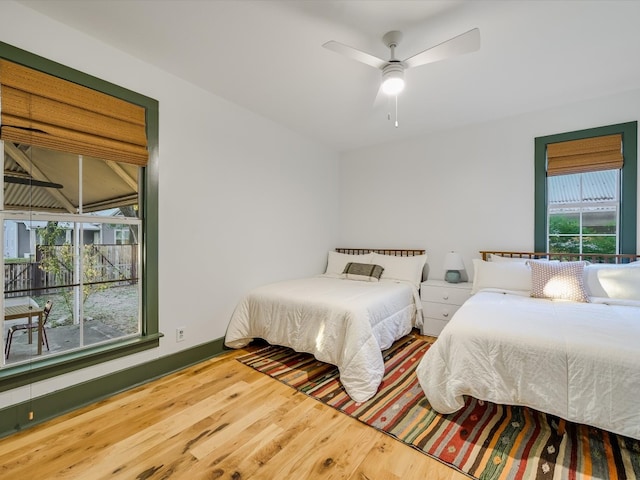 bedroom featuring ceiling fan, hardwood / wood-style flooring, and multiple windows