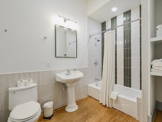 full bathroom featuring wainscoting, wood finished floors, toilet, tile walls, and shower / tub combo