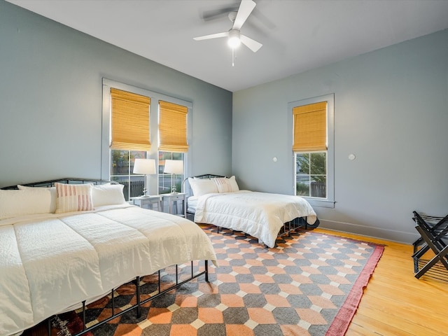 bedroom featuring multiple windows, hardwood / wood-style flooring, and ceiling fan