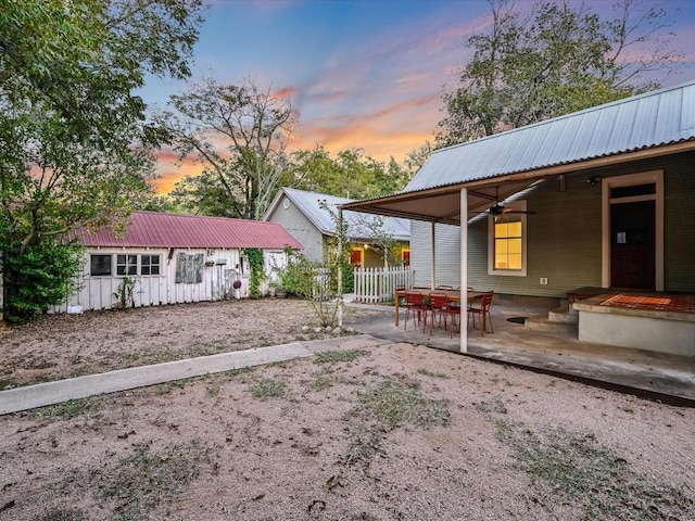 yard at dusk with fence, a ceiling fan, and a patio