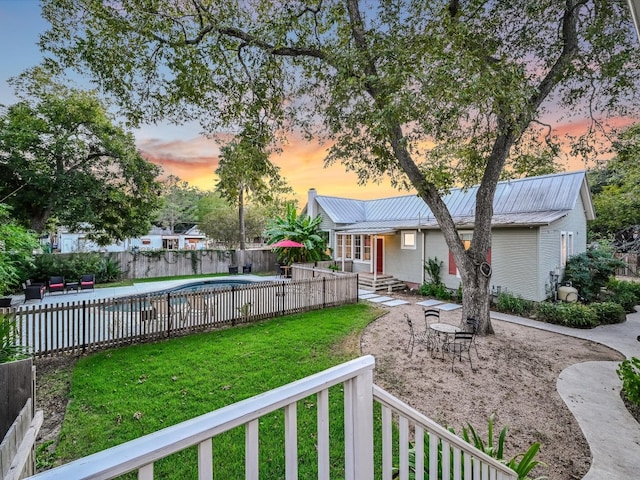 yard at dusk featuring a fenced in pool