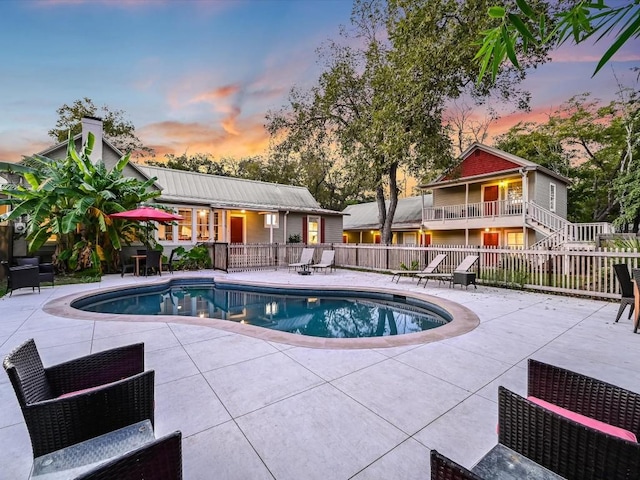 pool at dusk with a fenced in pool, fence, and a patio