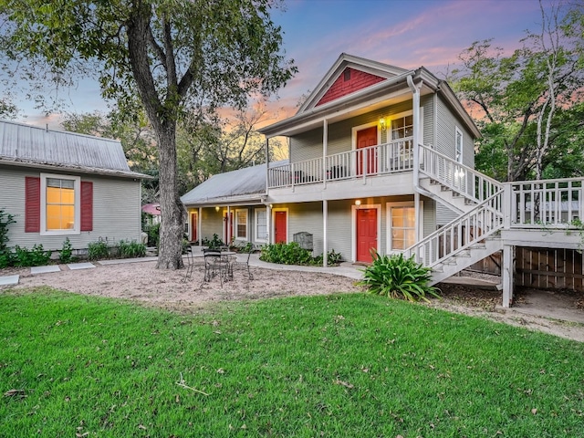 back house at dusk featuring a yard, a patio area, and a wooden deck