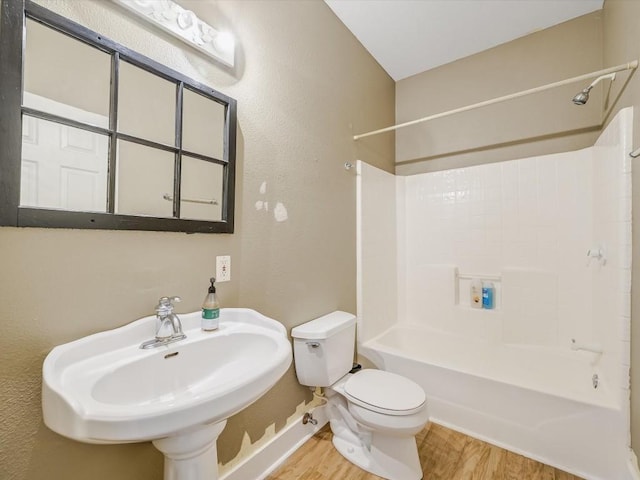 full bath featuring wood finished floors, a sink, baseboards, toilet, and tub / shower combination
