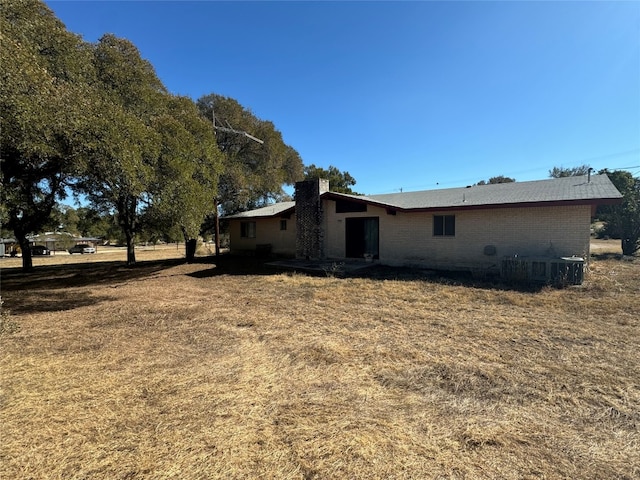 back of property featuring a lawn and central AC unit