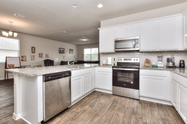 kitchen featuring kitchen peninsula, white cabinets, stainless steel appliances, and light wood-type flooring