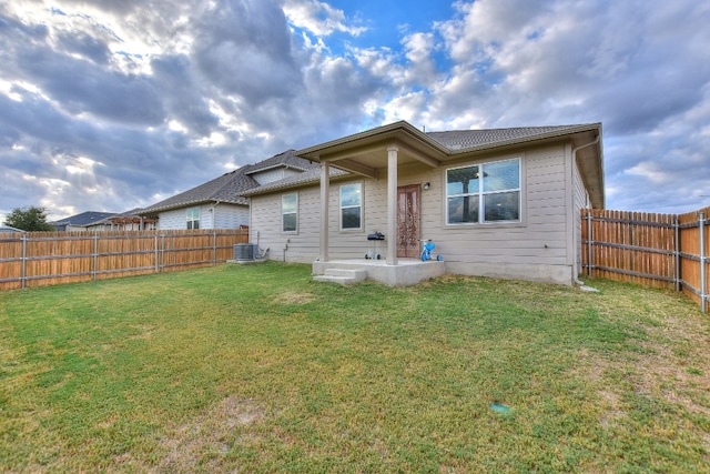 rear view of property with a yard and central AC unit