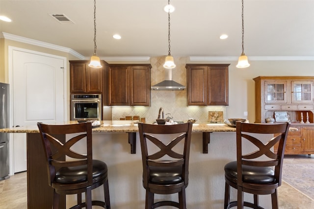 kitchen with a breakfast bar area, appliances with stainless steel finishes, hanging light fixtures, and a center island with sink