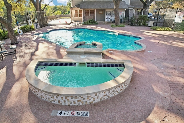 view of swimming pool featuring a hot tub and a patio