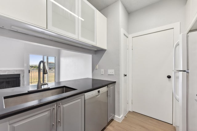 kitchen featuring light hardwood / wood-style floors, white cabinets, sink, and white appliances