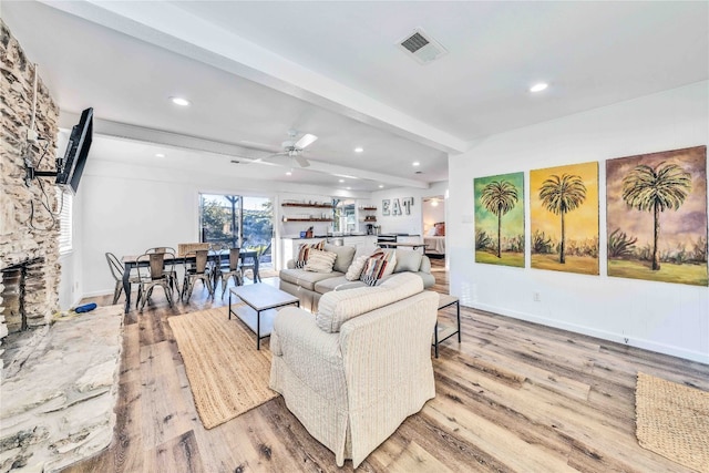 living room featuring beamed ceiling, light wood-type flooring, and ceiling fan