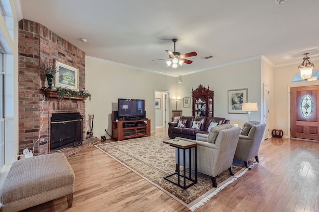 living room featuring crown molding, light hardwood / wood-style flooring, a fireplace, and ceiling fan