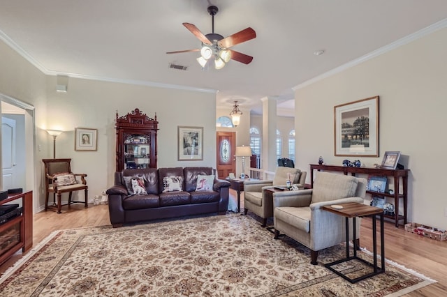 living room with ceiling fan, decorative columns, ornamental molding, and light wood-type flooring