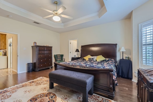 bedroom featuring dark wood-type flooring, crown molding, a tray ceiling, and ceiling fan