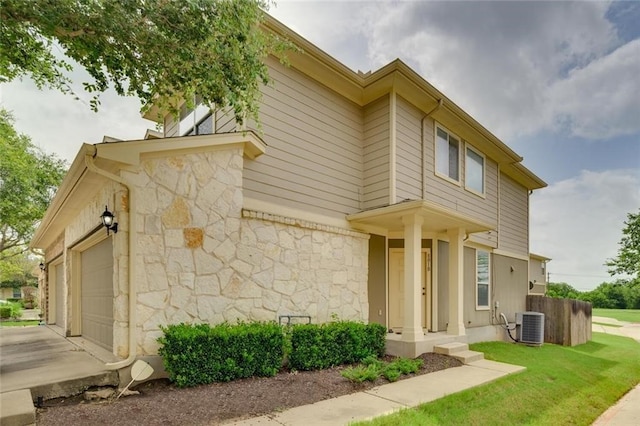 view of front of property with central air condition unit, a front lawn, and a garage